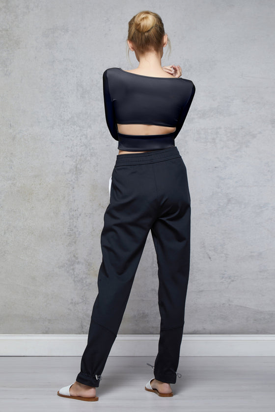Full body length back view of a woman wearing Bojana Ballet Top - Black and black sweatpants