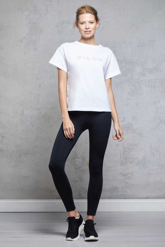 Full body length front view of a woman wearing Silou Tee - White and black leggings