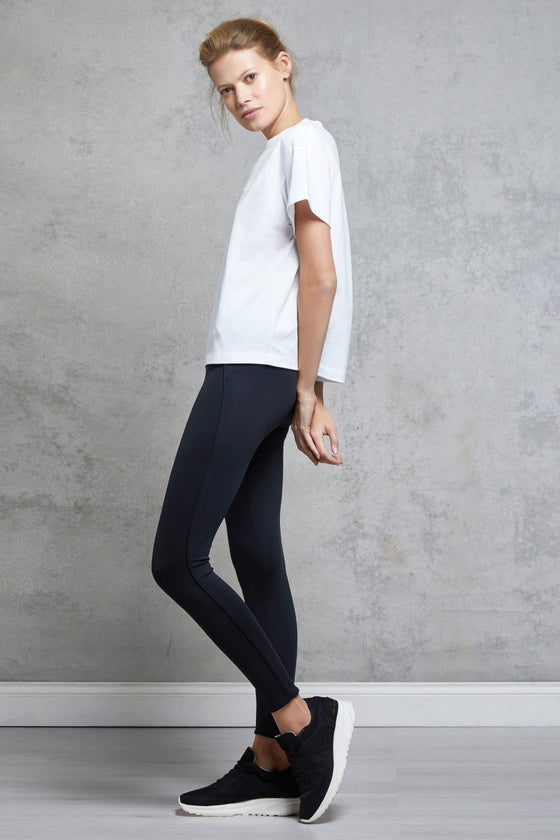 Full body length side view of a woman wearing Silou Tee - White and black leggings