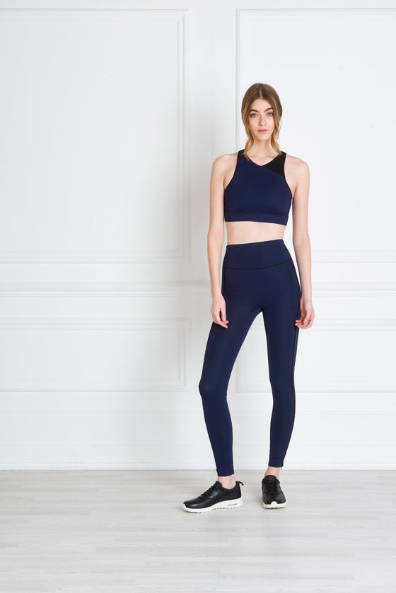 Full body length front view of a woman wearing Bridget Sports Bra - Navy and navy leggings