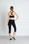 Full body length back view of a woman wearing Nadya Crop Legging - Black and a black crop top