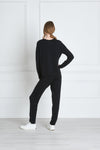 Full body length back view of a woman wearing Uma Sweatshirt - Black and black sweatpants